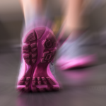 Close-up of a person’s running shoe with a pink sole in motion, showing the tread as they run on a surface with a motion blur effect.